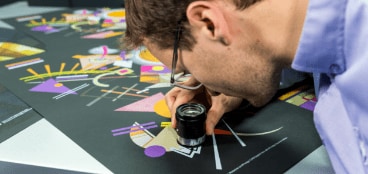 Expert checking the quality of HP Indigo print with a loupe